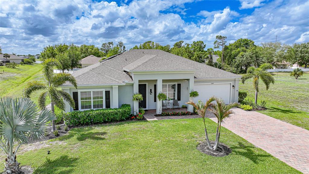 A single-story house with a brick driveway, palm trees, and a covered front entryway — 25091 PALISADE ROAD, PUNTA GORDA, FL