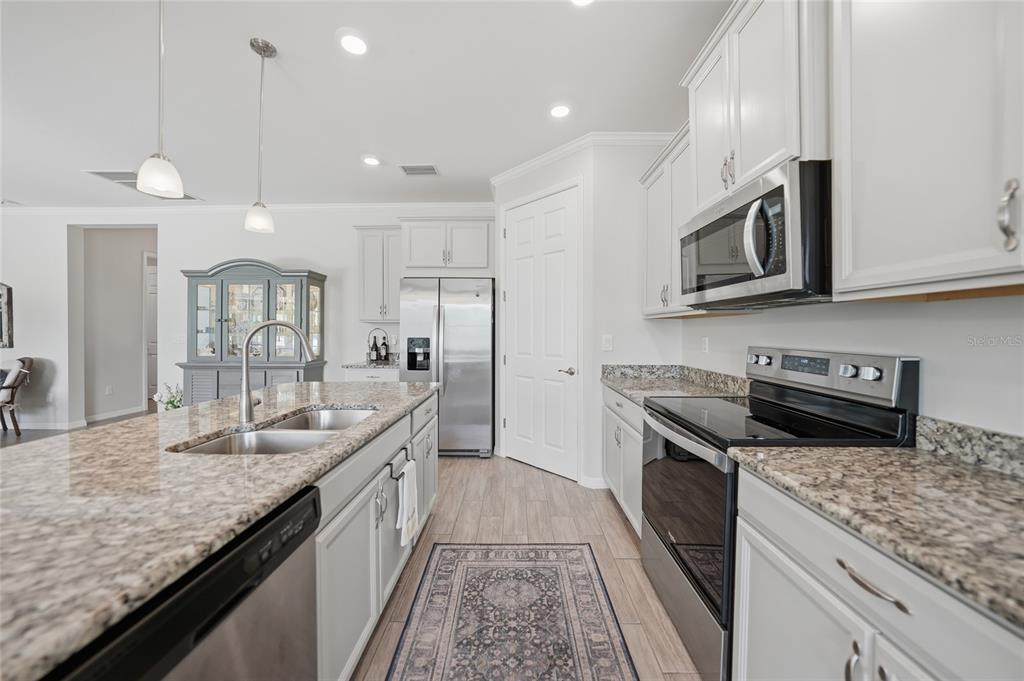 A kitchen features light gray cabinets, granite countertops, stainless steel appliances, and a central island — 25091 PALISADE ROAD, PUNTA GORDA, FL