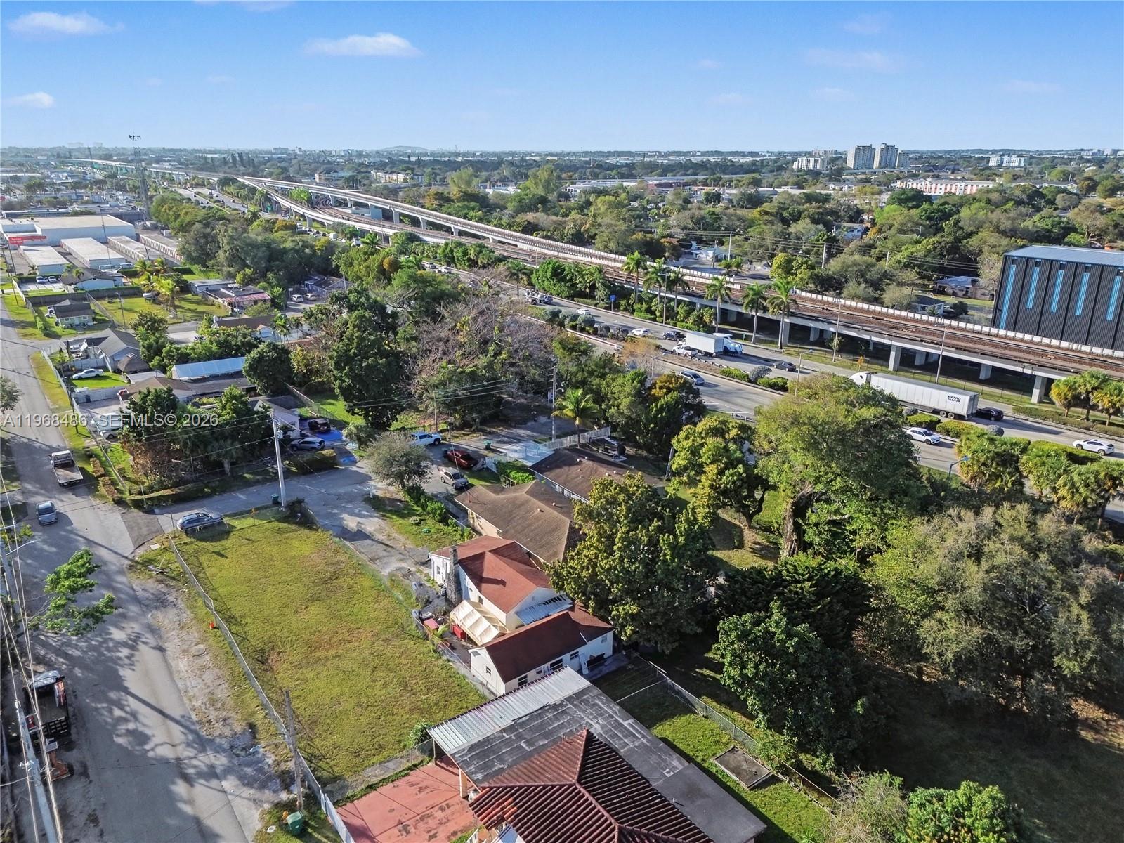 An aerial view shows residential houses, a large grassy lot, and an elevated highway nearby — 3801 NW 23rd Ave, Miami FL 33142, MIAMI, FL
