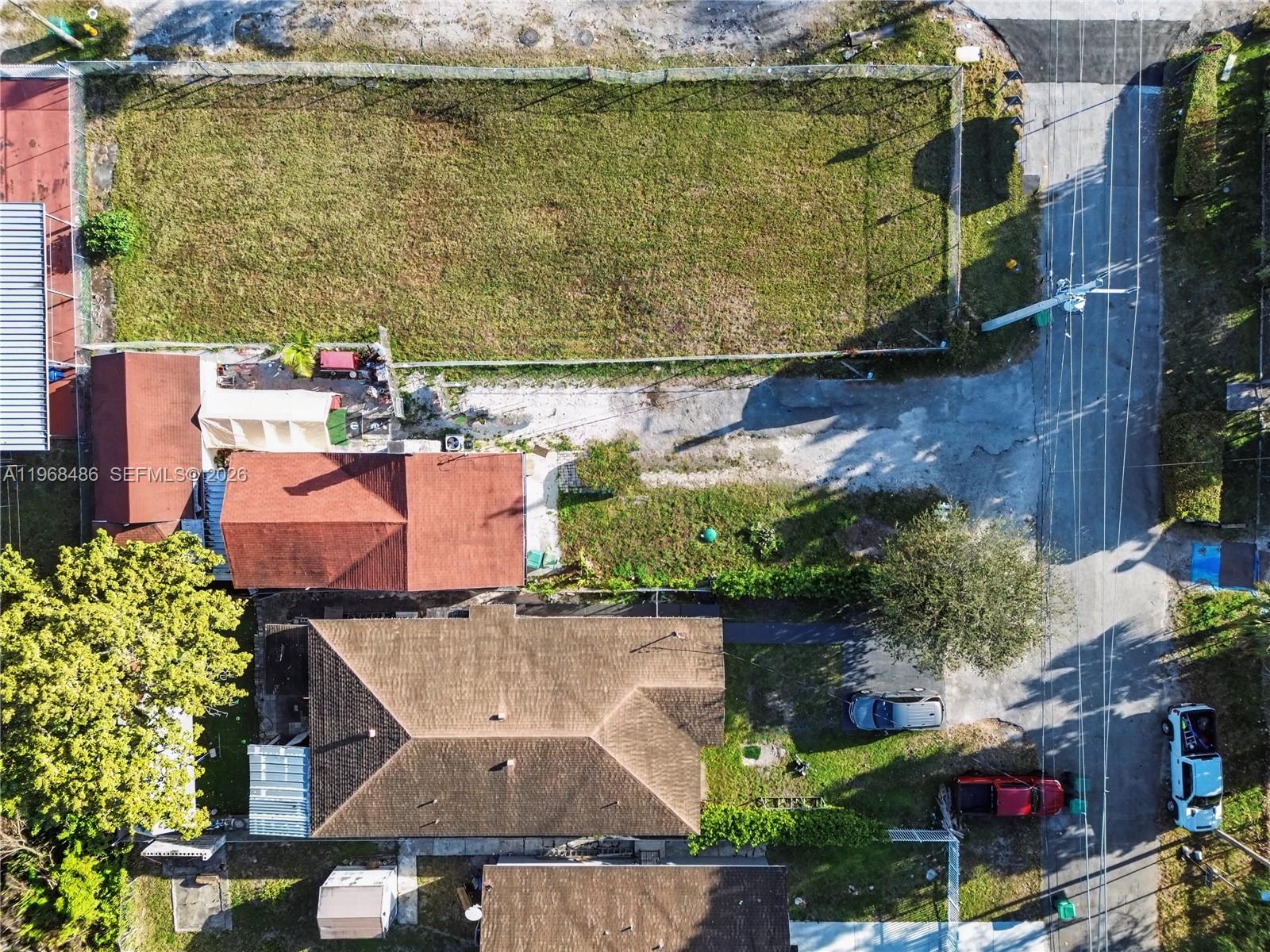 An aerial view shows a residential property with a fenced vacant lot and two houses — 3801 NW 23rd Ave, Miami FL 33142, MIAMI, FL