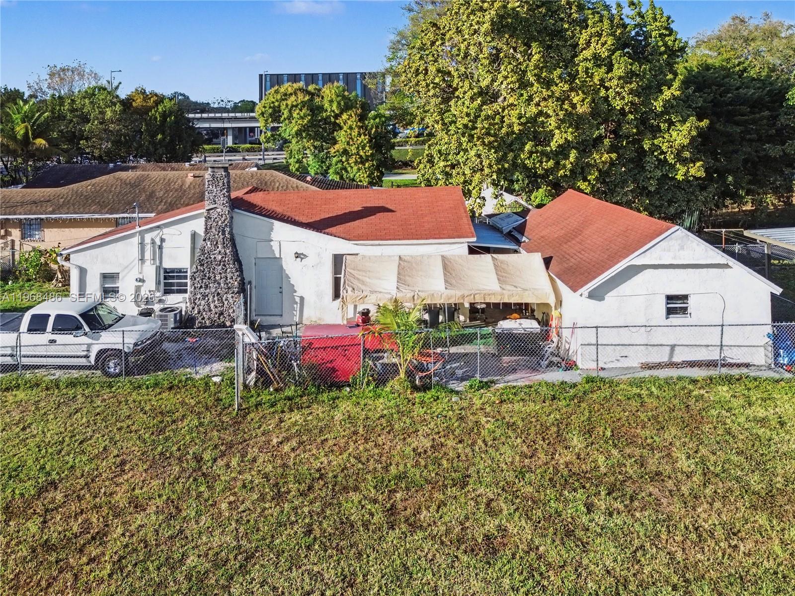 An exterior view of a white house with a stone chimney and a red roof — 3801 NW 23rd Ave, Miami FL 33142, MIAMI, FL