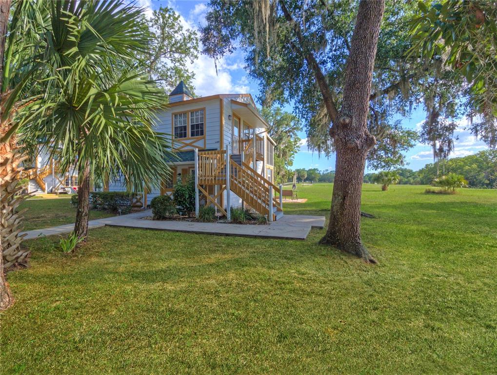 A two-story white building with an exterior wooden staircase sits on a grassy lawn — 7991 MIDWAY DRIVE TERRACE UNIT L201, OCALA, FL