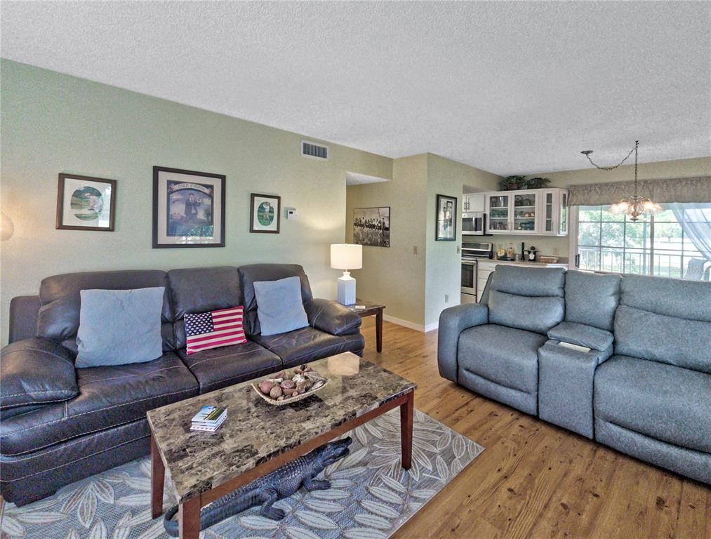 A living room features two sofas, a marble-topped coffee table, and wood flooring — 7991 MIDWAY DRIVE TERRACE UNIT L201, OCALA, FL
