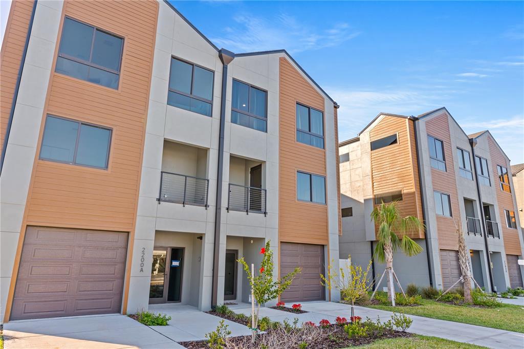 A modern multi-story townhouse complex features tan siding, concrete panels, and attached garages — 2200 BAY BOULEVARD UNIT B, INDIAN ROCKS BEACH, FL