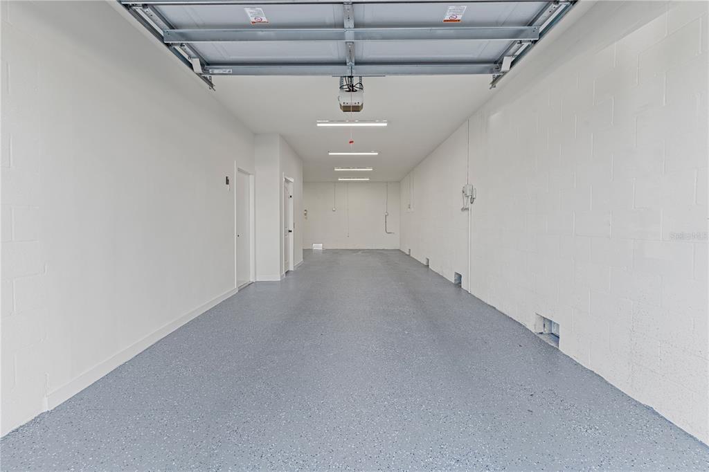 A long, empty garage features white block walls, a gray speckled floor, and overhead lighting — 2200 BAY BOULEVARD UNIT B, INDIAN ROCKS BEACH, FL