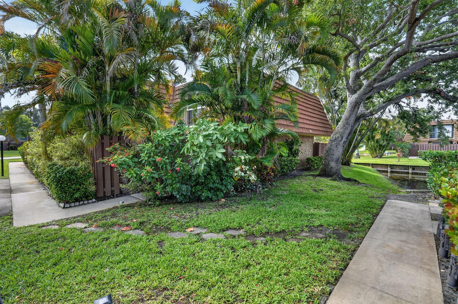 A residential building exterior with a brown roof, lush landscaping, and a canal-side lawn — 825 Center Street # 32b, Jupiter FL 33458, JUPITER, FL