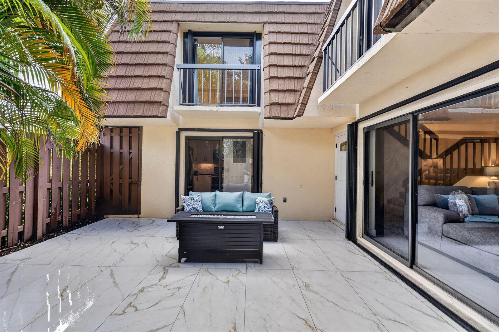 A patio with white marble-look tiles, a fire pit table, and a sofa faces a house — 825 Center Street # 32b, Jupiter FL 33458, JUPITER, FL