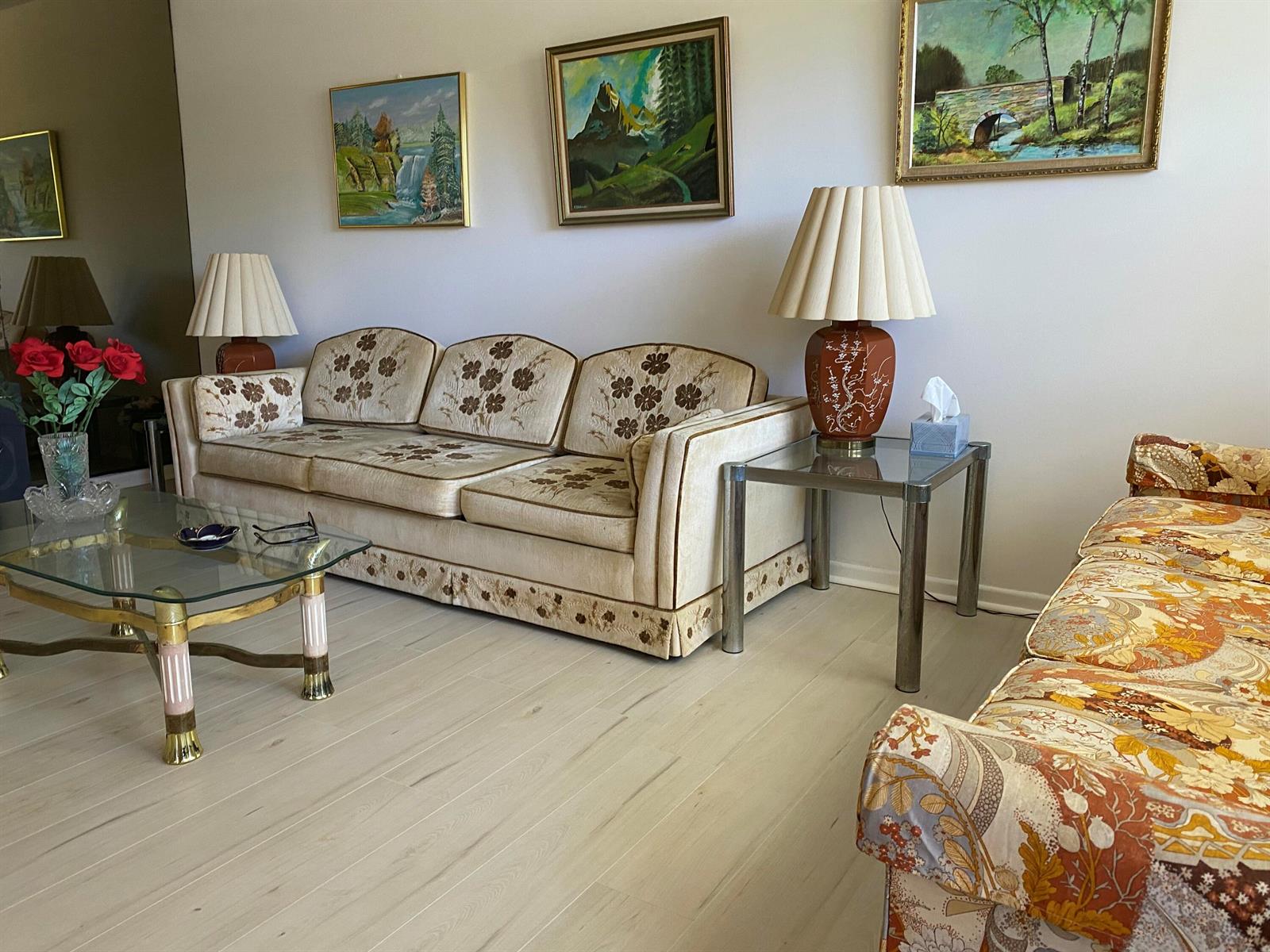 A living room features a floral sofa, a glass coffee table, and framed landscape paintings — 2054 Ainslie D, Boca Raton FL 33434, BOCA RATON, FL
