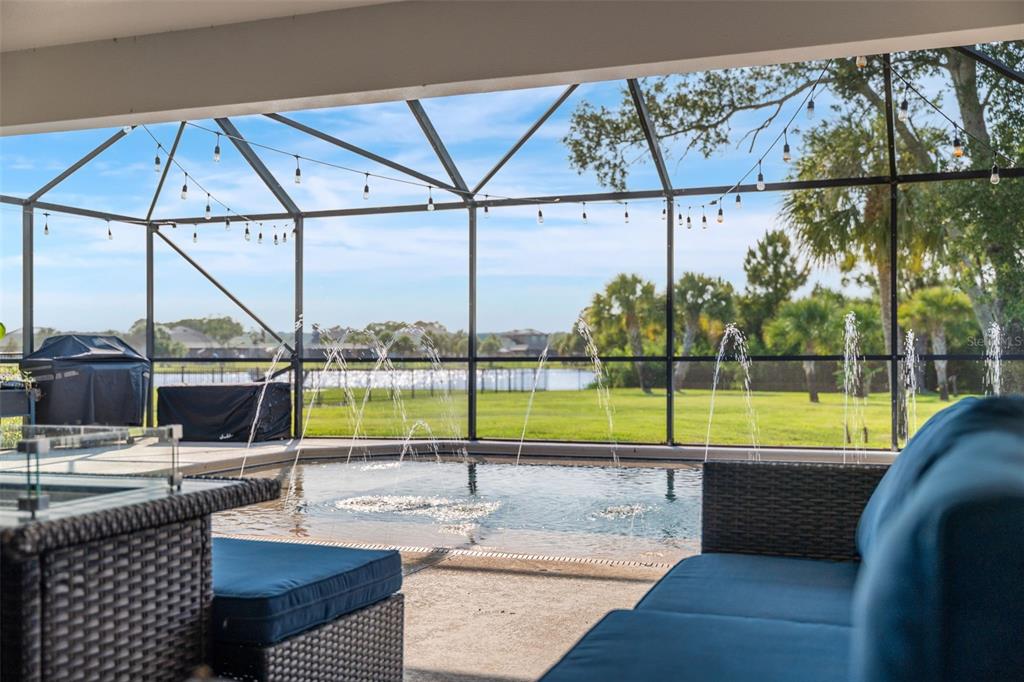 A covered patio with a pool, water fountains, and outdoor seating overlooking a grassy yard — 3897 PROVINCE DRIVE, MELBOURNE, FL