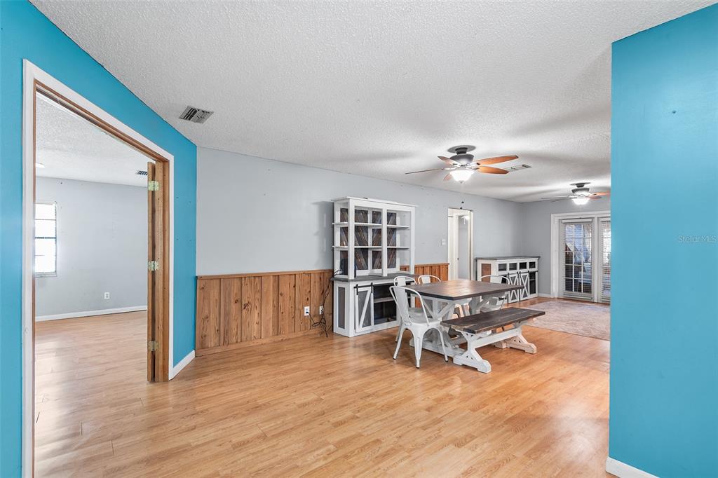 A dining area with wood wainscoting, laminate flooring, and a white hutch and table set — 905 VAN DRIVE, AUBURNDALE, FL