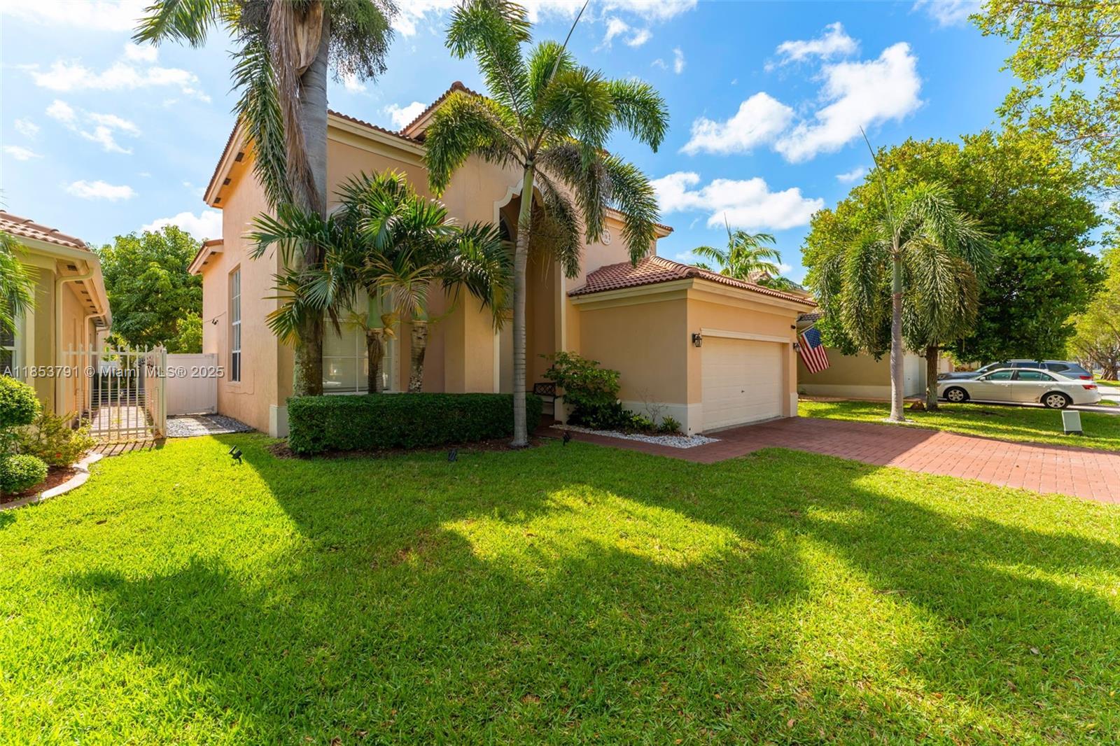 A two-story tan house with a tile roof, palm trees, and a brick driveway — 1755 NE 37th Ave # 0, Homestead FL 33033, HOMESTEAD, FL