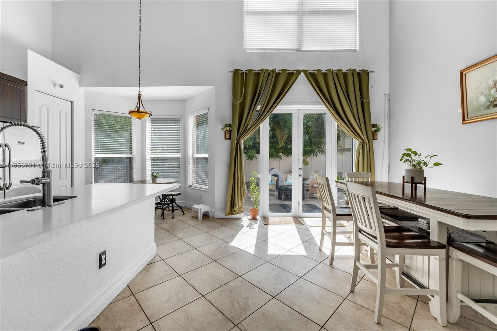 A kitchen and dining area with tile floors, a breakfast bar, and glass patio doors — 1755 NE 37th Ave # 0, Homestead FL 33033, HOMESTEAD, FL