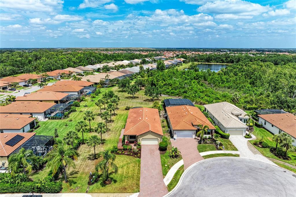 An aerial view shows a suburban neighborhood with houses featuring orange tile roofs and pools — 10111 MALACHITE DRIVE, BRADENTON, FL