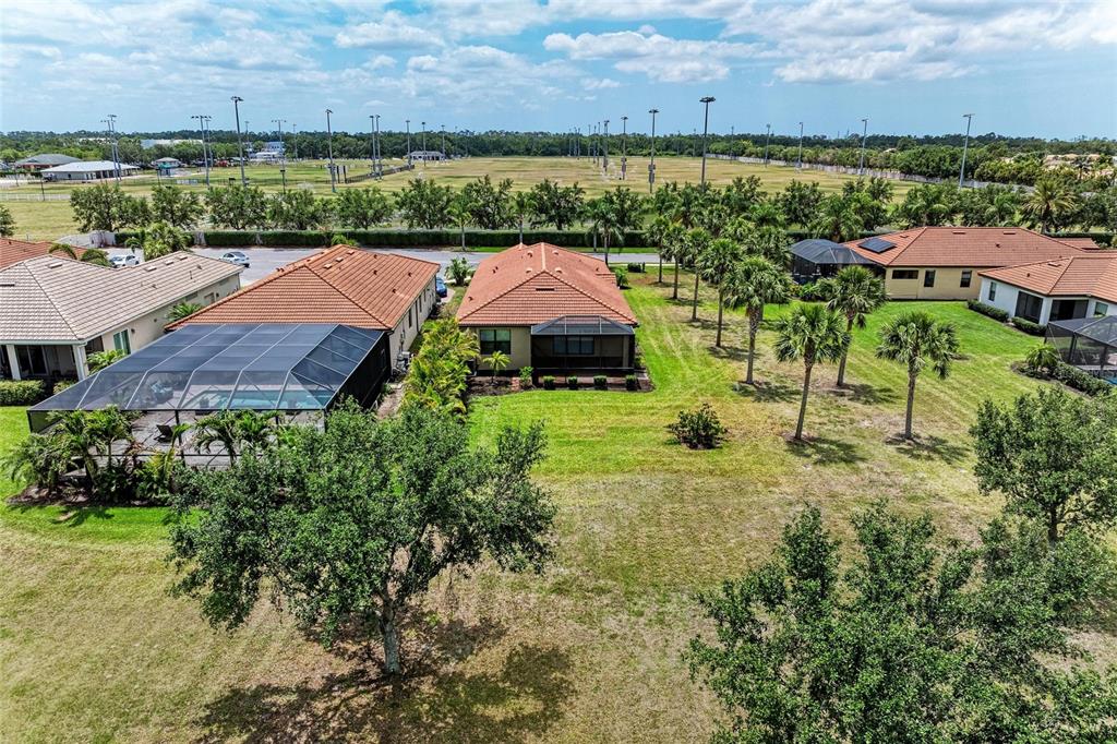 An aerial view shows several suburban houses with tiled roofs and screened-in pools — 10111 MALACHITE DRIVE, BRADENTON, FL