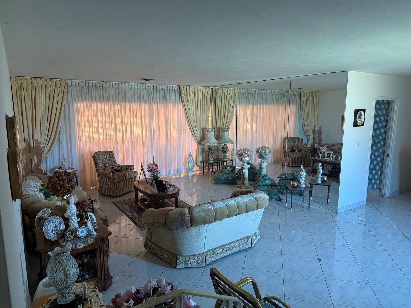 A living room features tile flooring, a mirrored wall, and floor-to-ceiling curtains — 8230 SW 87th Terrace, Miami FL 33143, MIAMI, FL