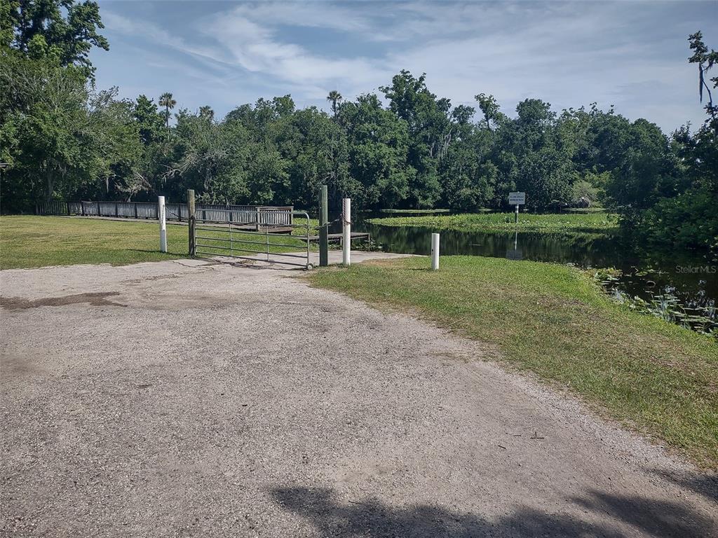 A gravel boat ramp leads to a body of water with a wooden dock nearby — 56508 BLUE CREEK ROAD, ASTOR, FL