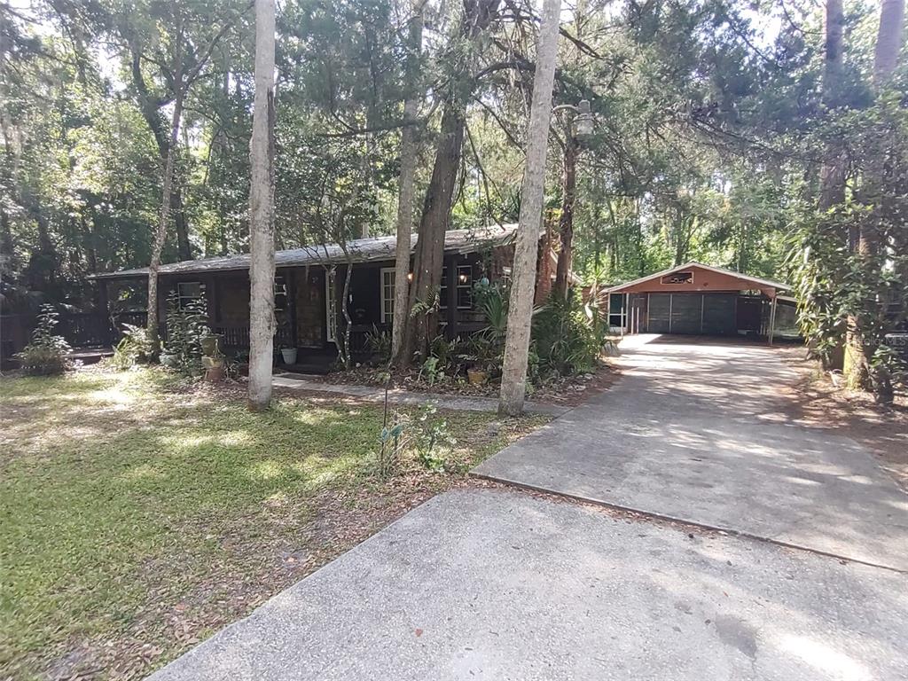 A single-story house with a detached garage sits on a wooded lot with a driveway — 56508 BLUE CREEK ROAD, ASTOR, FL