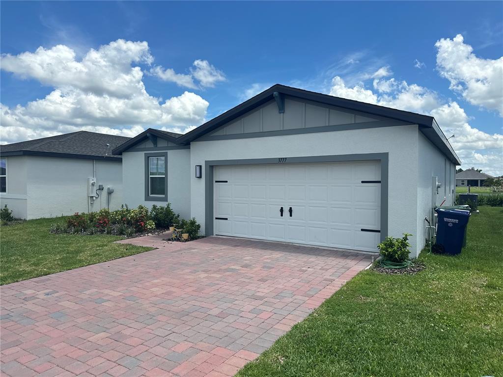 A single-story house features a white stucco exterior, a two-car garage, and a paver driveway — 3777 GIORGIO DRIVE, WINTER HAVEN, FL