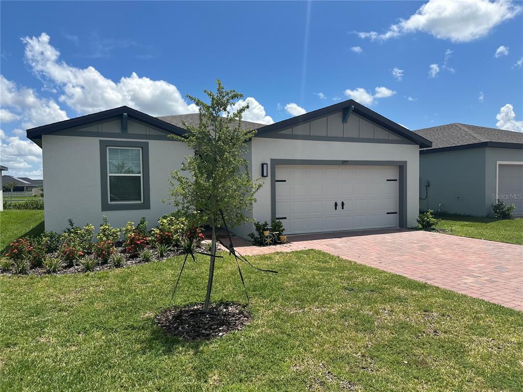 A single-story house with a light-colored exterior, a two-car garage, and a landscaped front yard — 3777 GIORGIO DRIVE, WINTER HAVEN, FL