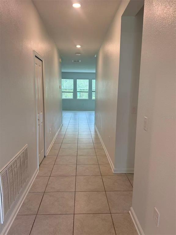 A tiled hallway leads toward a living area with three windows and recessed lighting — 16493 CHAMPLAIN STREET, CLERMONT, FL
