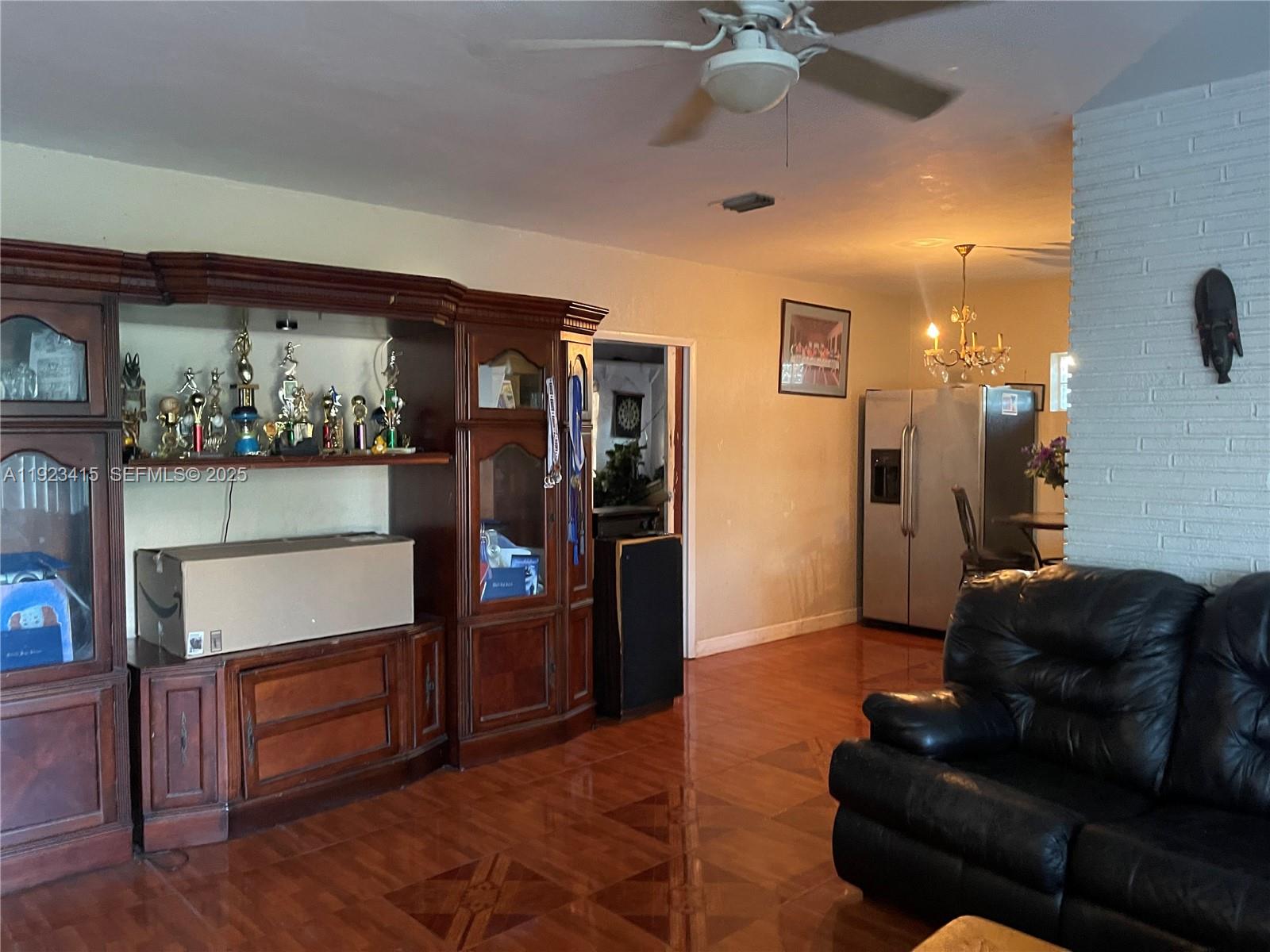 A living room features a large wooden display cabinet, tiled floors, and a ceiling fan — 3880 NW 6th St, Lauderhill FL 33311, LAUDERHILL, FL