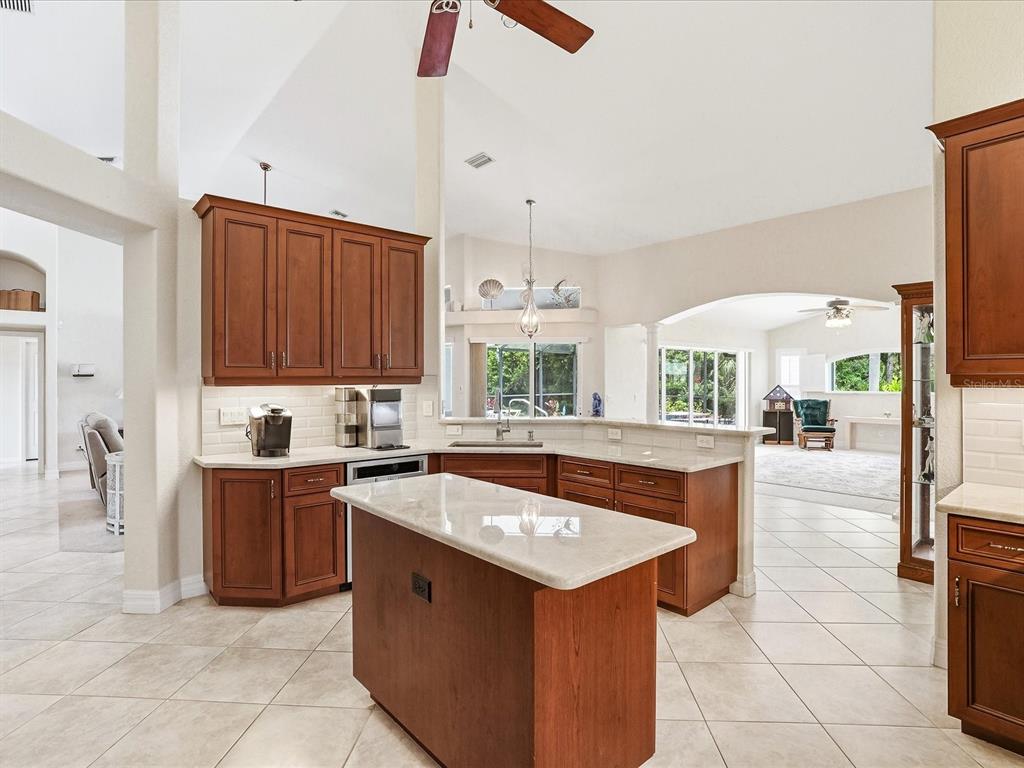 A kitchen with wood cabinets, stone countertops, a center island, and tile flooring — 61 PINE VALLEY COURT, ROTONDA WEST, FL
