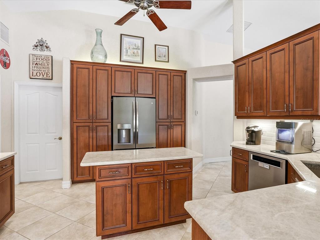 A kitchen with wood cabinets, stainless steel appliances, a center island, and tile flooring — 61 PINE VALLEY COURT, ROTONDA WEST, FL