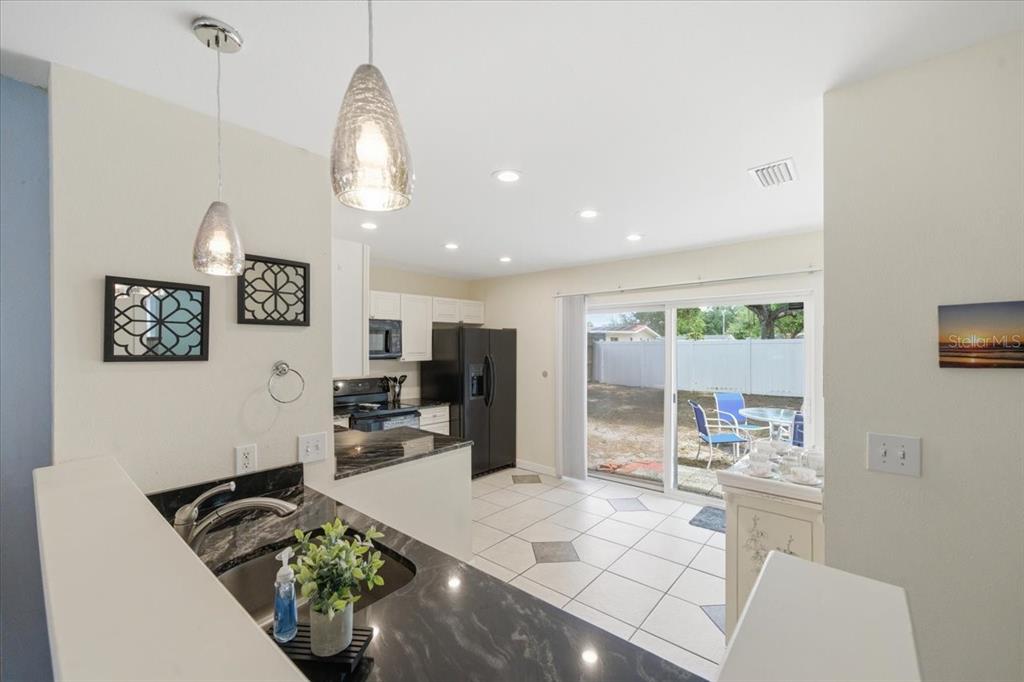A kitchen with dark countertops, white cabinets, and a sliding glass door leading outside — 12291 MALLORY DRIVE, LARGO, FL