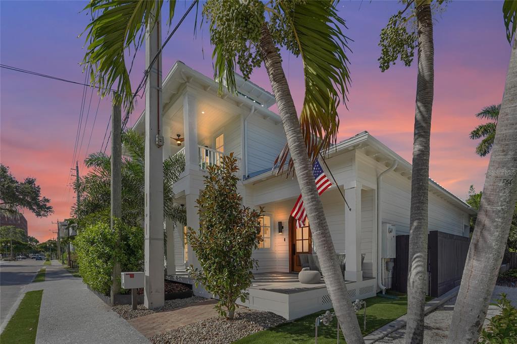 A white two-story house with a front porch and an American flag at sunset — 417 N OSPREY AVENUE, SARASOTA, FL