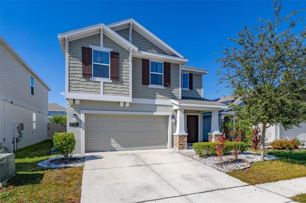 A two-story house with a beige garage, shingle siding, and a concrete driveway — 1066 BERRY LANE, DAVENPORT, FL