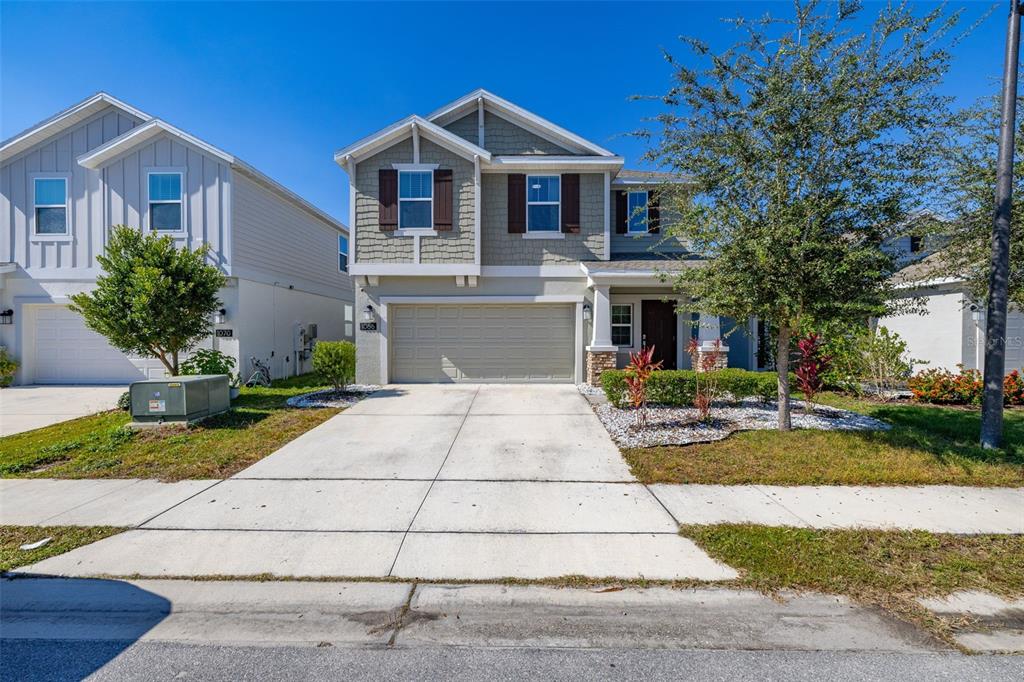 A two-story suburban house with a beige garage, gray siding, and a concrete driveway — 1066 BERRY LANE, DAVENPORT, FL