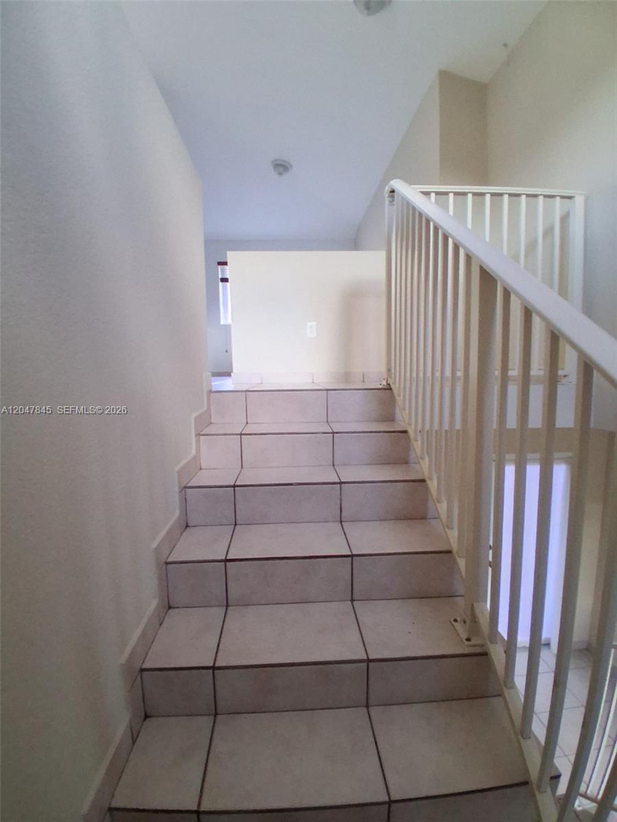 A staircase with light-colored tile steps and a white metal railing leads upward — 17318 NW 74th Ave # 202, Hialeah FL 33015, HIALEAH, FL