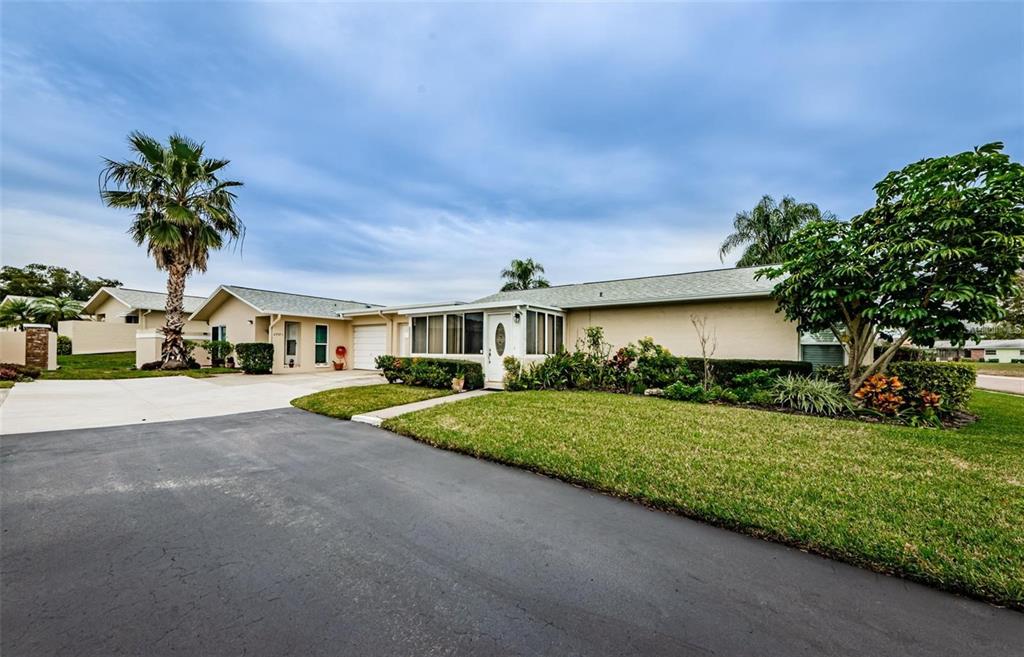 A single-story house with a tan exterior, a palm tree, and a paved driveway — 2739 SHERBROOKE LANE UNIT B, PALM HARBOR, FL
