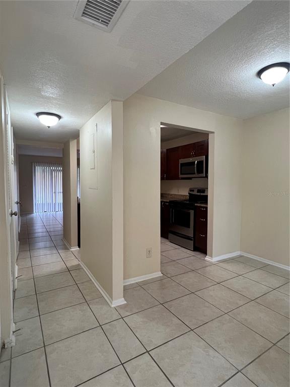 A tiled hallway leads to a kitchen with stainless steel appliances and dark wood cabinets — 1428 HIGHLAND RIDGE CIRCLE, BRANDON, FL