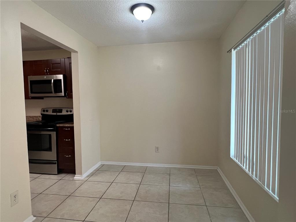 A dining area with beige walls, tile flooring, and a window with vertical blinds — 1428 HIGHLAND RIDGE CIRCLE, BRANDON, FL