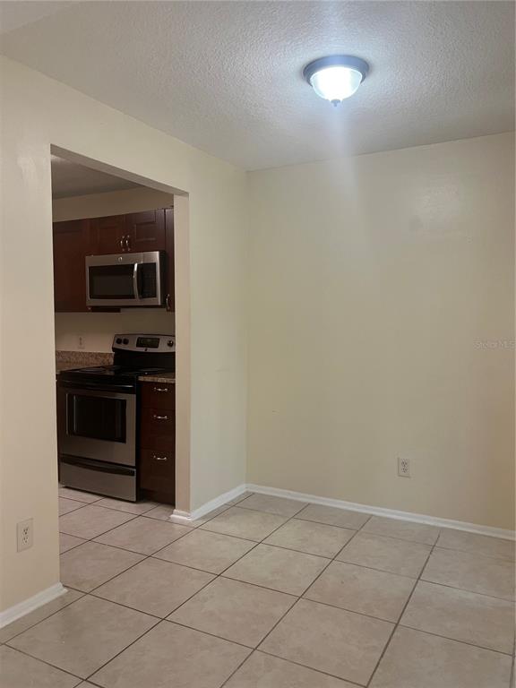 A dining area with tile flooring leads into a kitchen with dark wood cabinets — 1428 HIGHLAND RIDGE CIRCLE, BRANDON, FL
