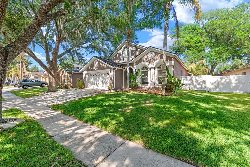 A two-story suburban house with a tan stucco exterior, a two-car garage, and green lawn — 4814 PORTOBELLO CIRCLE, VALRICO, FL