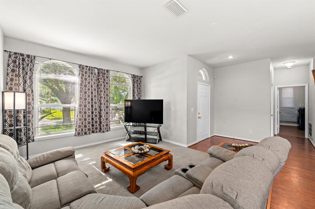 A living room features gray carpet, a sectional sofa, a coffee table, and large windows — 4814 PORTOBELLO CIRCLE, VALRICO, FL
