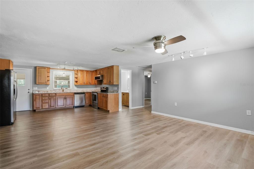 An open-concept kitchen and living area featuring light wood flooring and wooden cabinetry — 8317 LIMAN DRIVE, NEW PORT RICHEY, FL