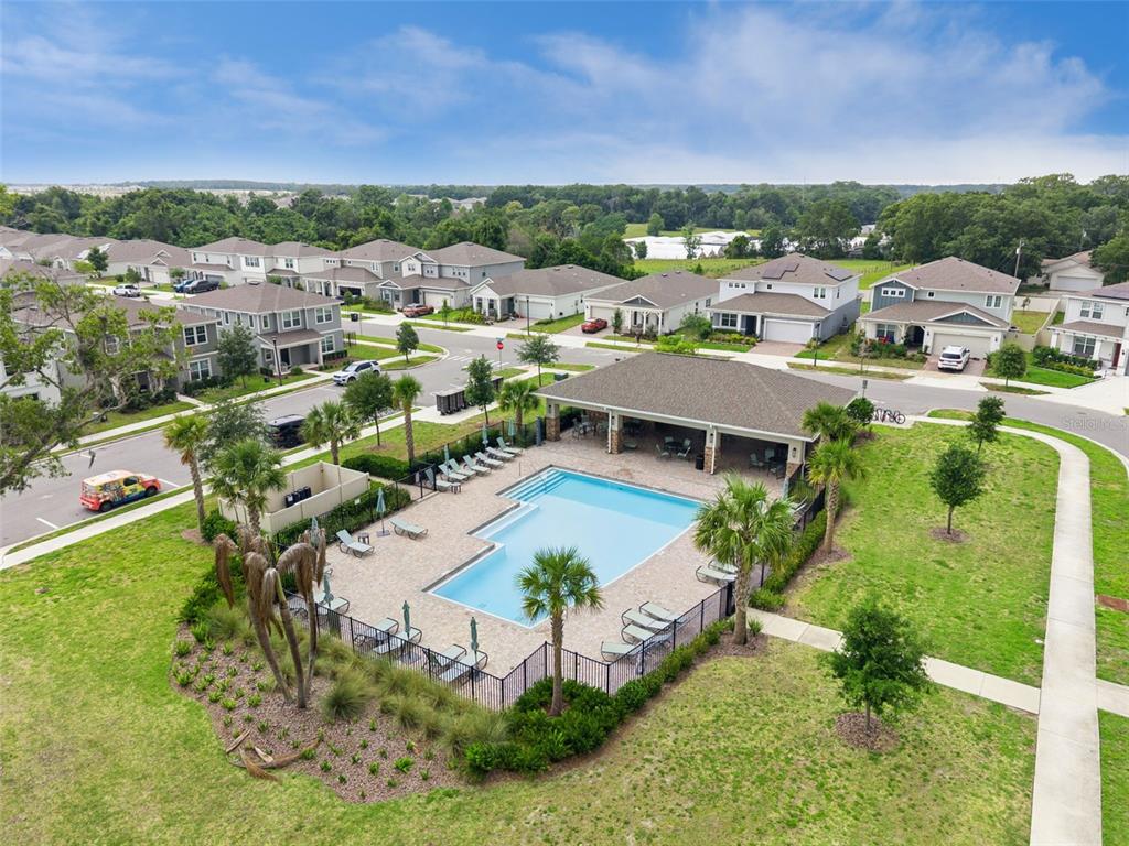 An aerial view shows a community swimming pool and covered patio surrounded by residential houses — 4062 FEATHER TREE DRIVE, APOPKA, FL