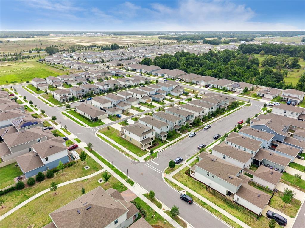 An aerial view shows a suburban neighborhood with multiple houses, paved streets, and green spaces — 4062 FEATHER TREE DRIVE, APOPKA, FL