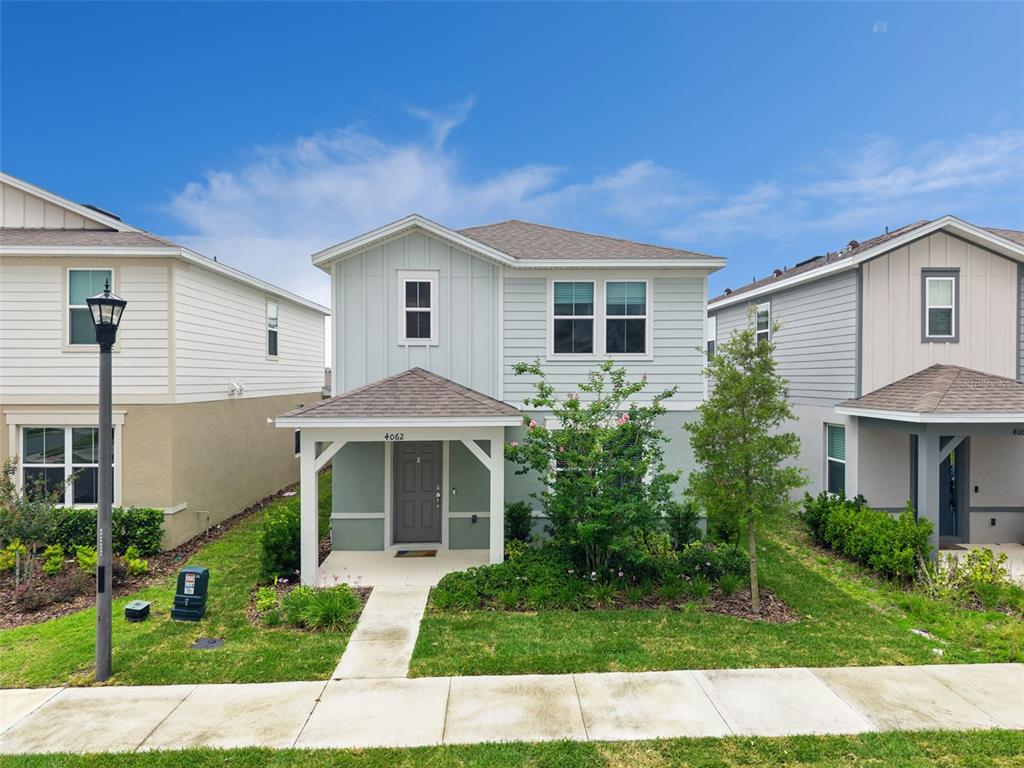 A two-story house with light blue siding, a covered front porch, and a small front yard — 4062 FEATHER TREE DRIVE, APOPKA, FL