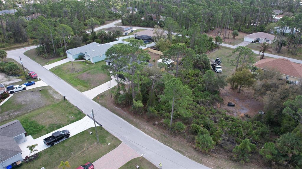 An aerial view shows a residential street with houses, wooded lots, and parked vehicles — GANTRY ROAD, NORTH PORT, FL