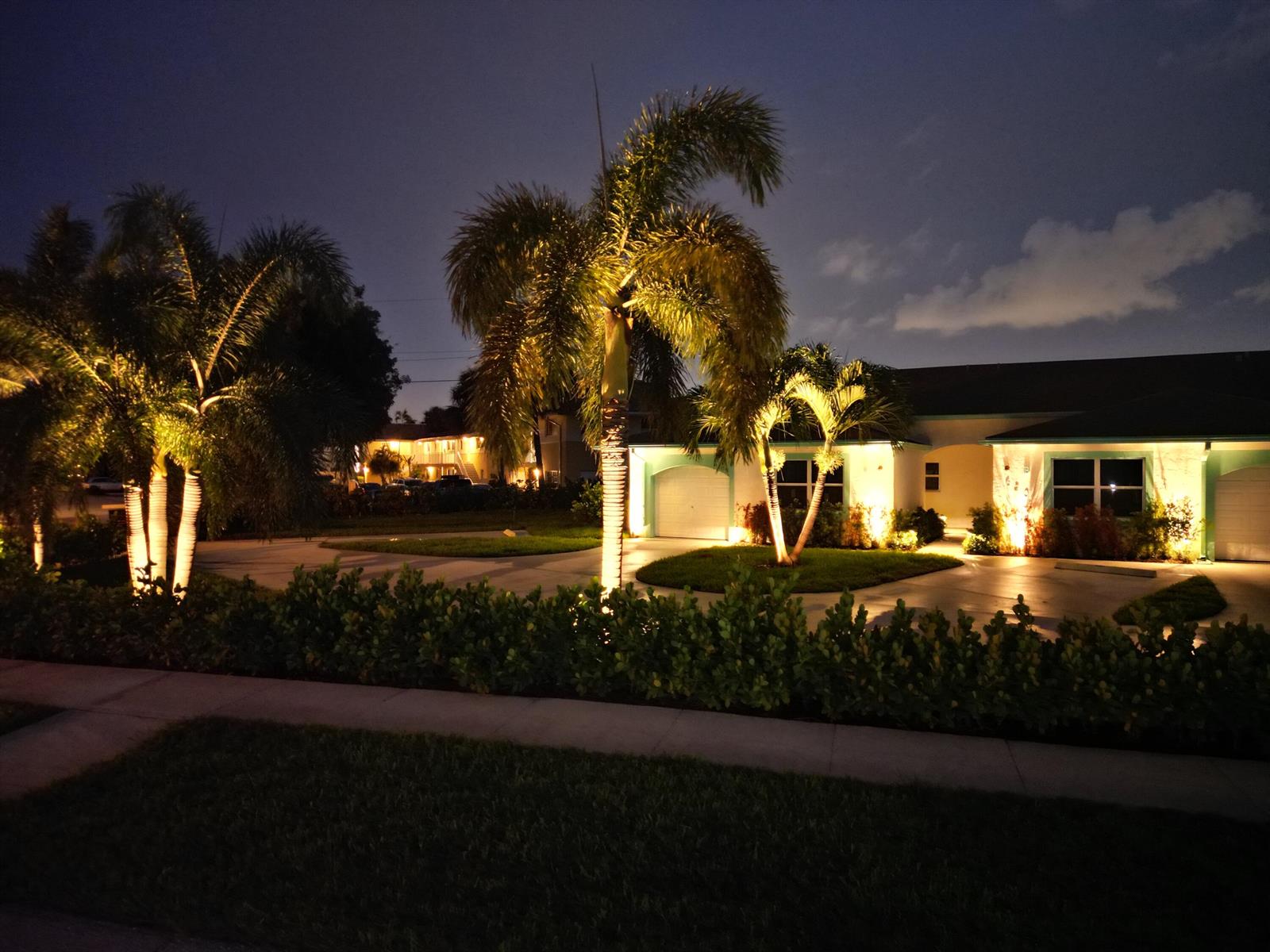 A house exterior at night features illuminated palm trees and a paved driveway — 620 Southwind Circle # A, North Palm Beach FL 33408, NORTH PALM BEACH, FL