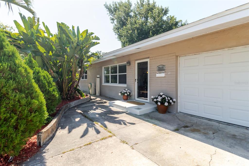 The exterior of a house features a front door, a welcome mat, and two potted plants — 3597 27TH AVENUE S, ST PETERSBURG, FL