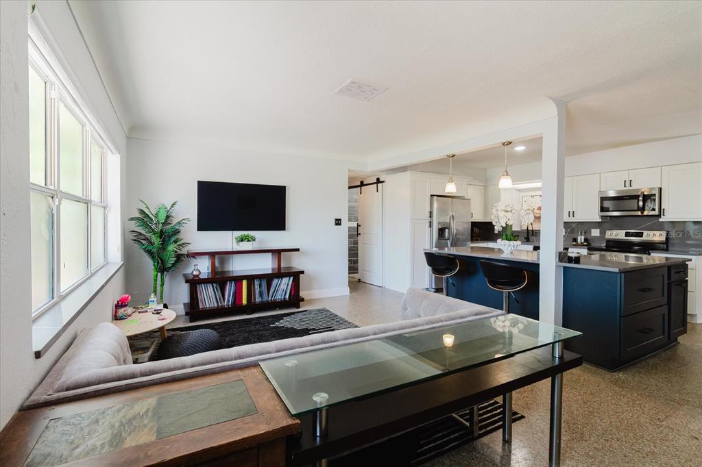 A living room features a glass-topped desk, a gray sofa, and a wall-mounted television — 3597 27TH AVENUE S, ST PETERSBURG, FL