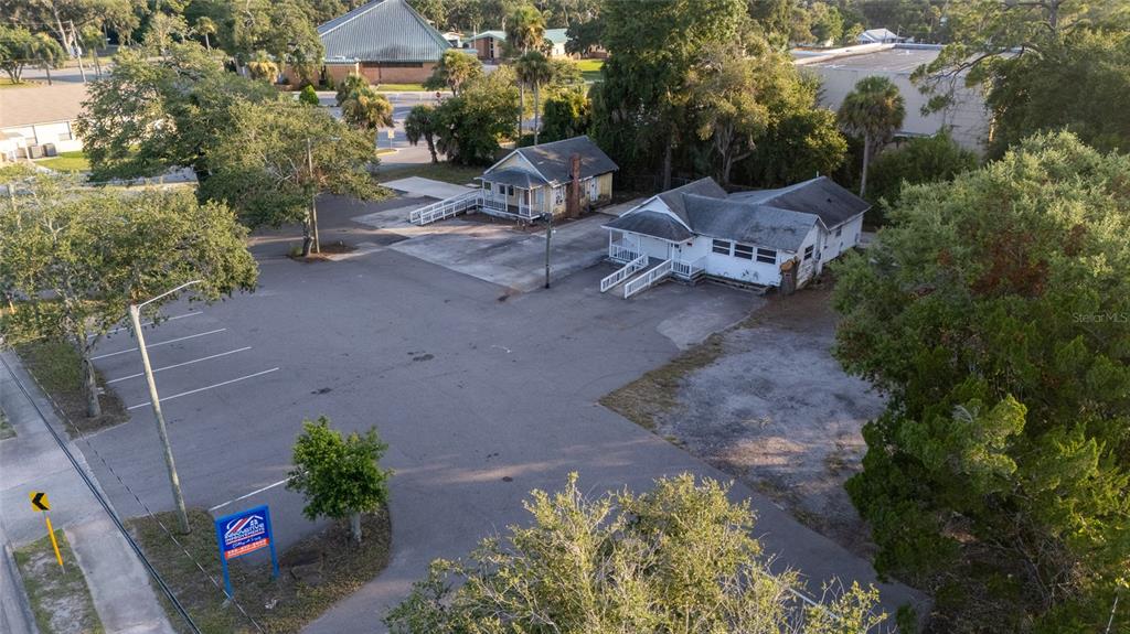 An aerial view shows two small buildings situated on a large, paved parking lot — 1042 N DIXIE FREEWAY, NEW SMYRNA BEACH, FL