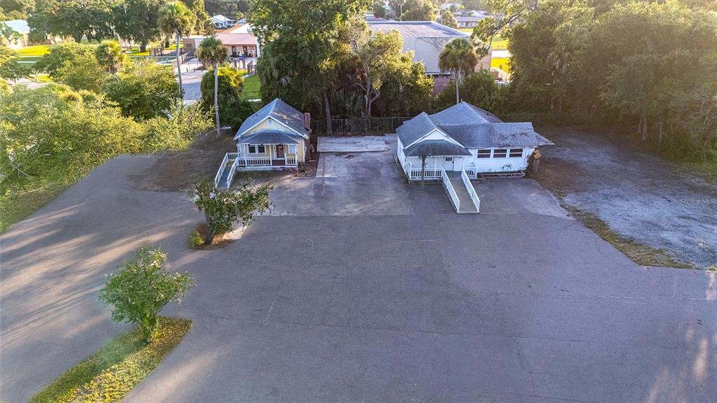 An aerial view shows two small houses with wheelchair ramps situated on a large paved lot — 1042 N DIXIE FREEWAY, NEW SMYRNA BEACH, FL