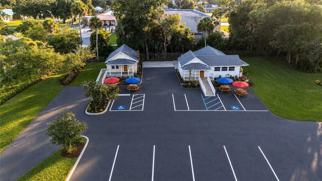An aerial view shows two small buildings with parking spaces and outdoor seating areas — 1042 N DIXIE FREEWAY, NEW SMYRNA BEACH, FL