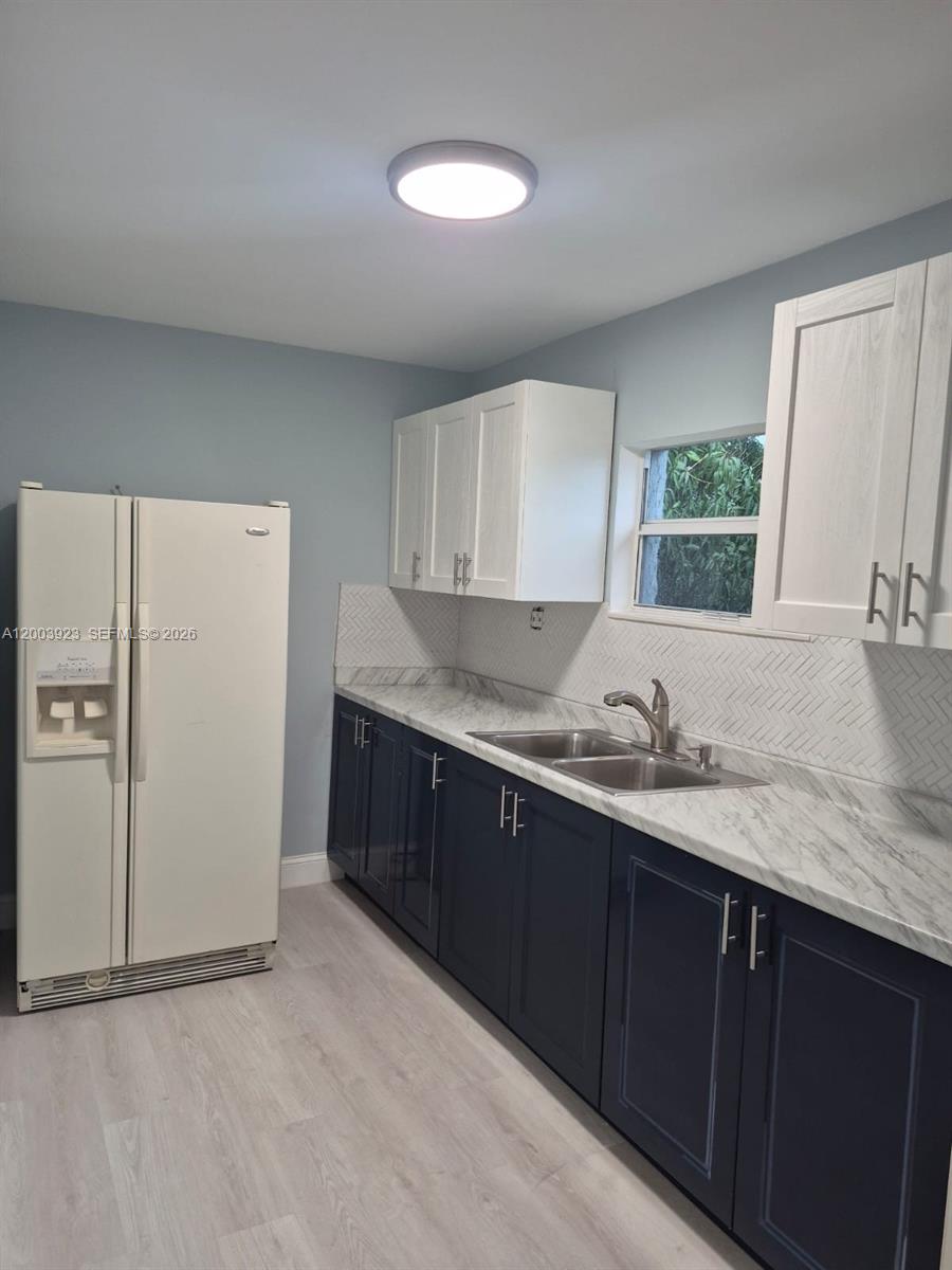 A kitchen features dark blue lower cabinets, white upper cabinets, and a marble-patterned countertop — 1231 NW 101st St # 2, Miami FL 33147, MIAMI, FL